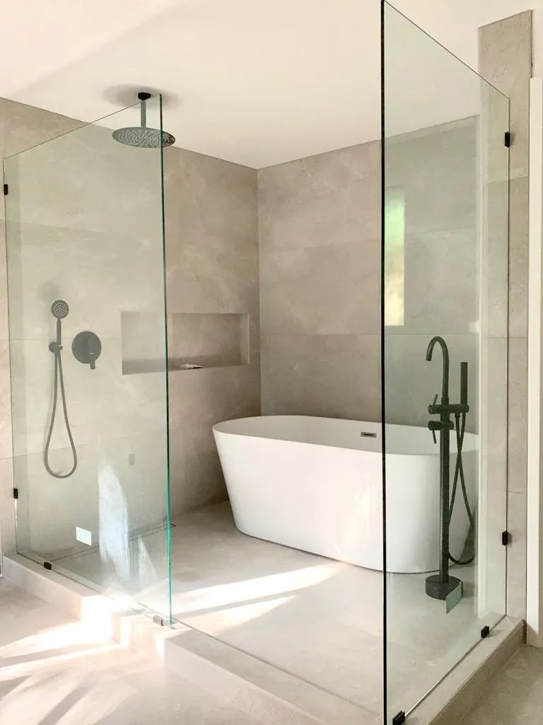 A freestanding tub and shower within a glass enclosure, with dark fixtures and a recessed niche. Redmond, WA