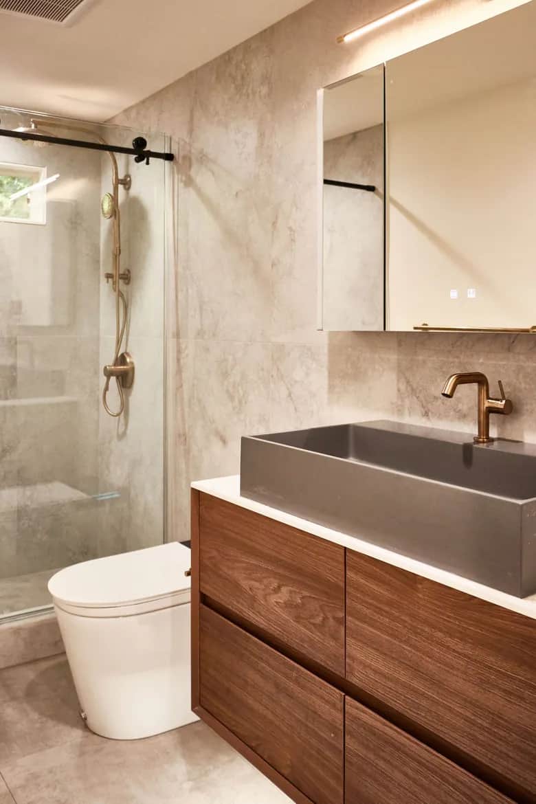 A glass shower enclosure, large-format stone tile and a concrete sink above walnut drawers. Bellevue, WA