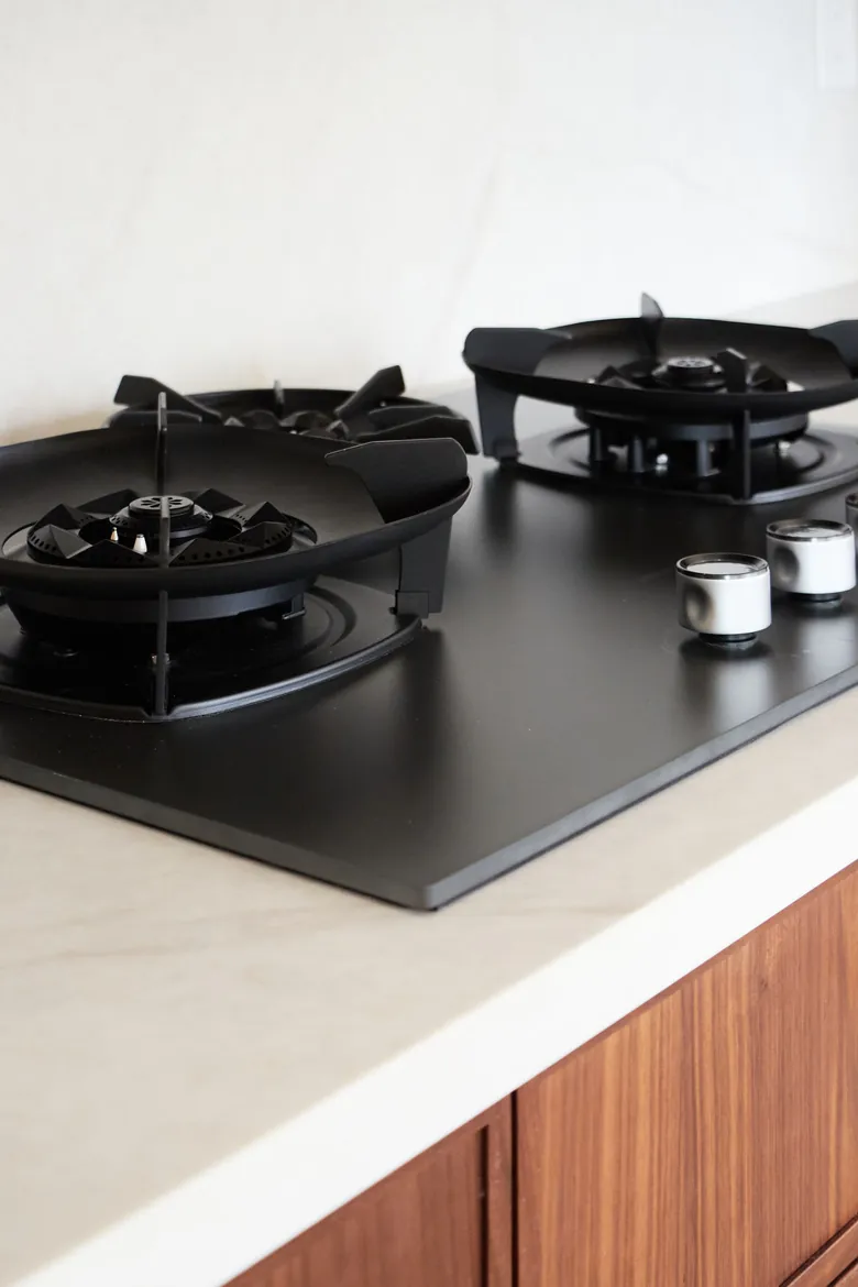 Black gas burners and a white quartz-look counter above walnut cabinet fronts. Bellevue, WA