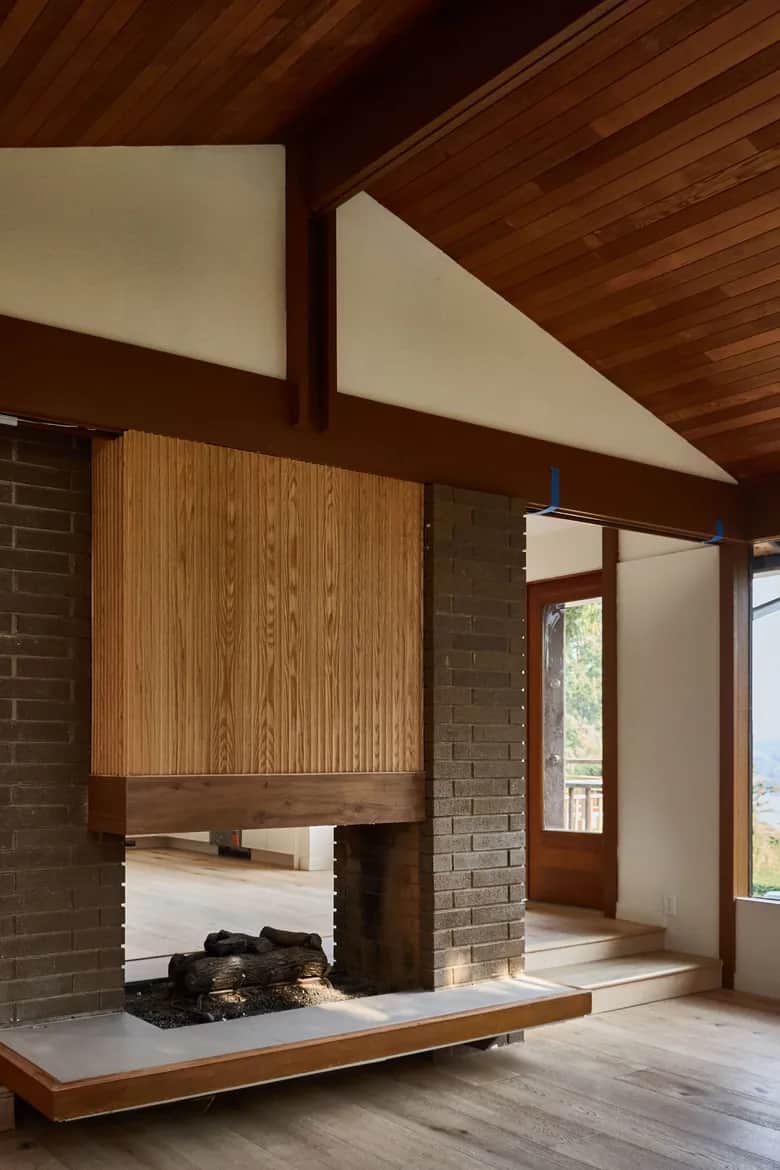 A wood ceiling and exposed beams above a brick fireplace with a wood surround and hearth. Bellevue, WA