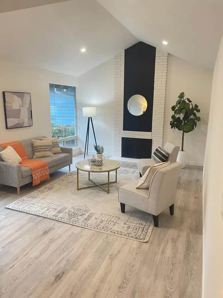 A vaulted living area with pale flooring and a white brick fireplace with a dark vertical accent. Bellevue, WA
