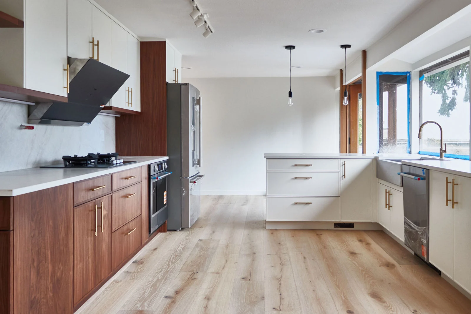 A walnut kitchen with white stone counters beside a wide window in a Bellevue whole-home remodel.