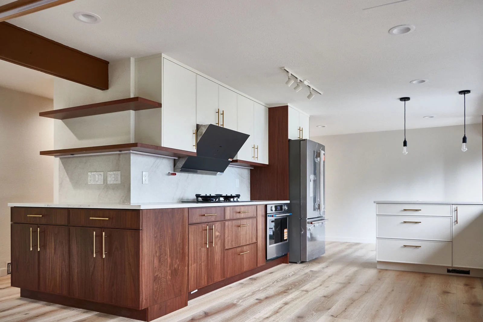 Walnut cabinetry, white counters and open shelves in a kitchen with wood flooring, Bellevue whole-home remodel.